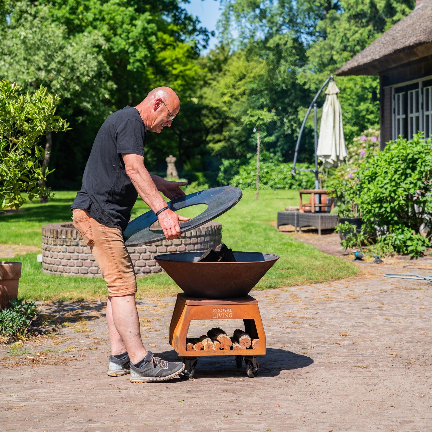 Barbecue Plancha Grill Brasero en acier Corten avec grandes roues, rangement pour le bois et plaque de cuisson Ø80cm