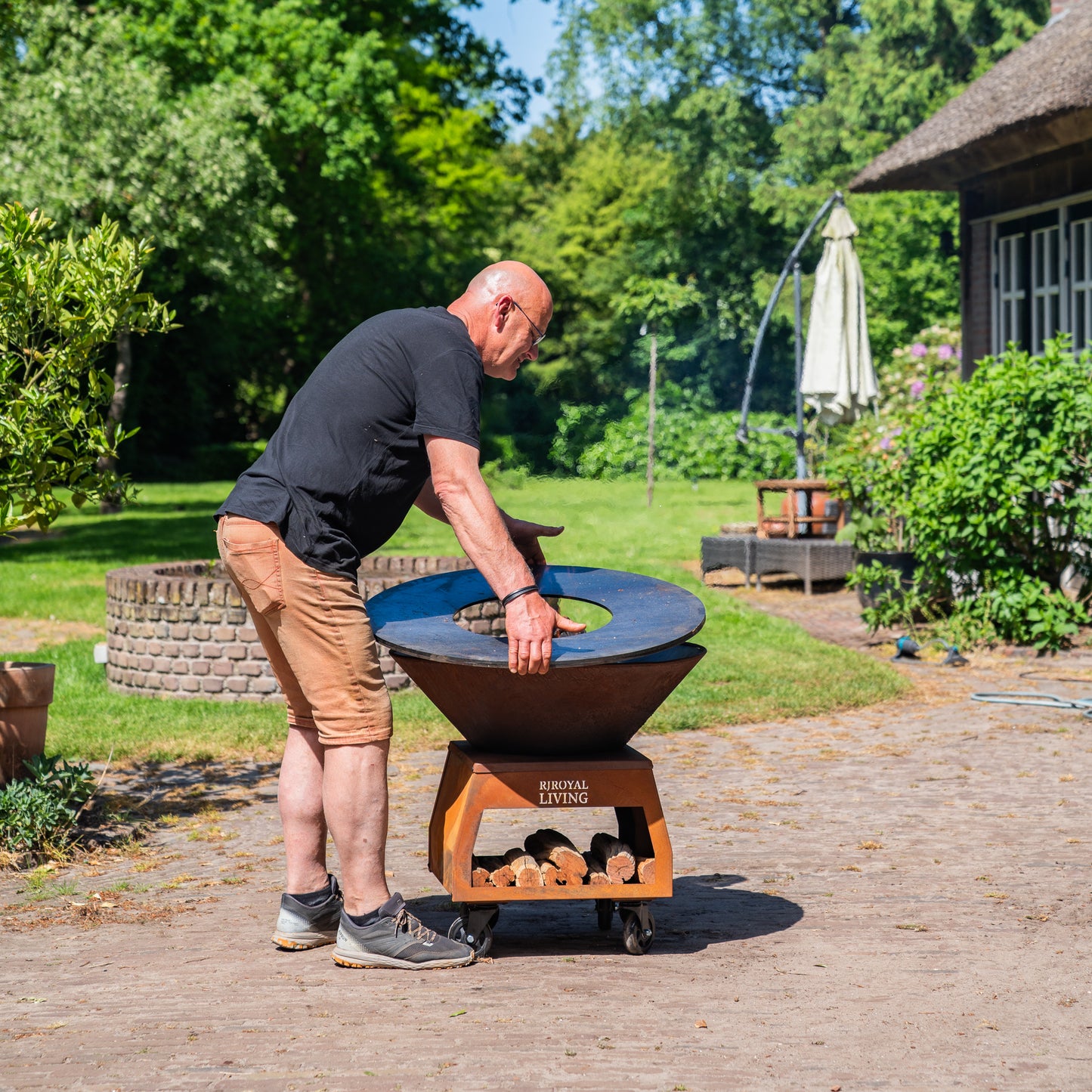 Barbecue Plancha Grill Brasero en acier Corten avec grandes roues, rangement pour le bois et plaque de cuisson Ø80cm